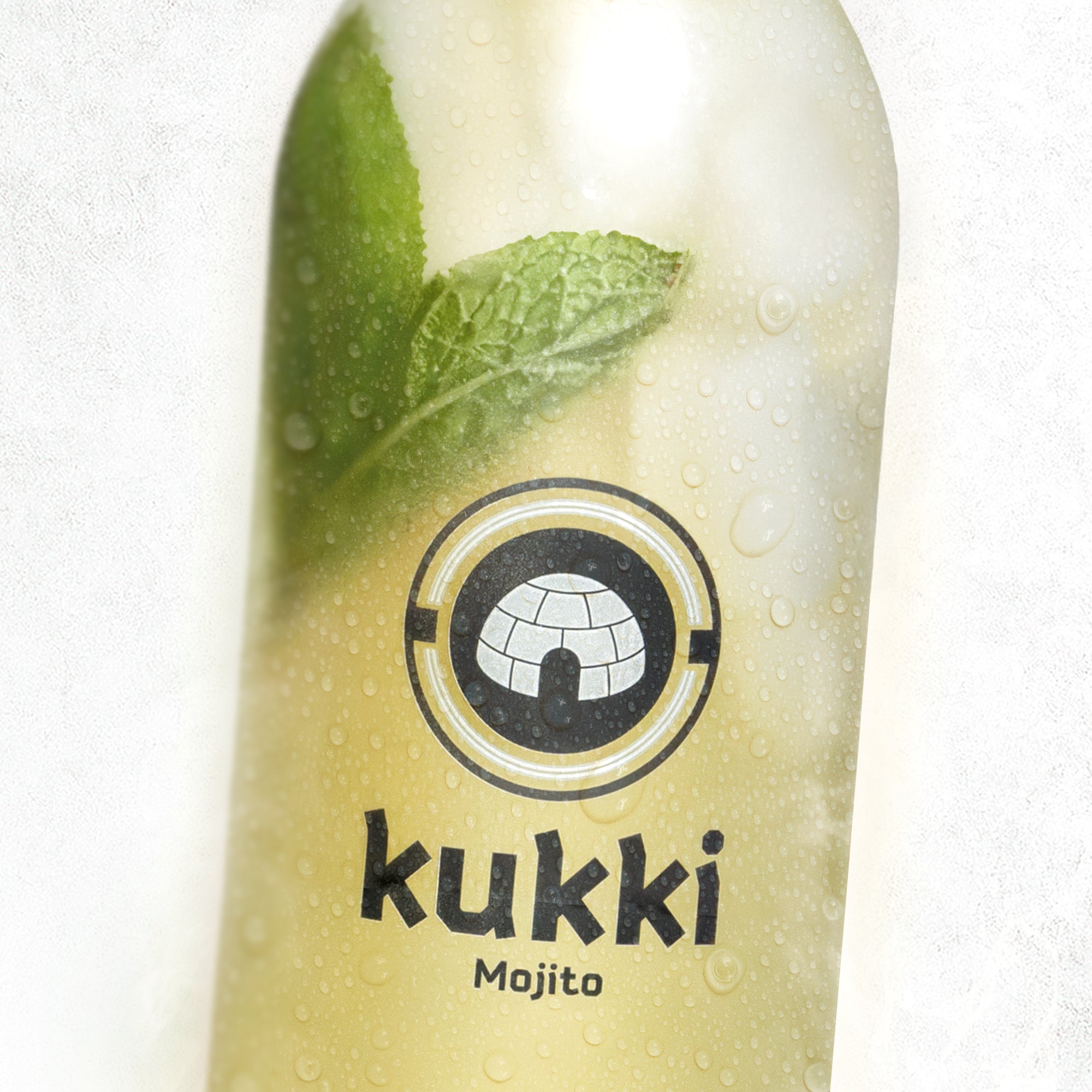Gekühlte Glasflasche mit kukki Cocktail Mojito und frischen Minzblättern, Tau auf der Flasche zeigt Erfrischung.