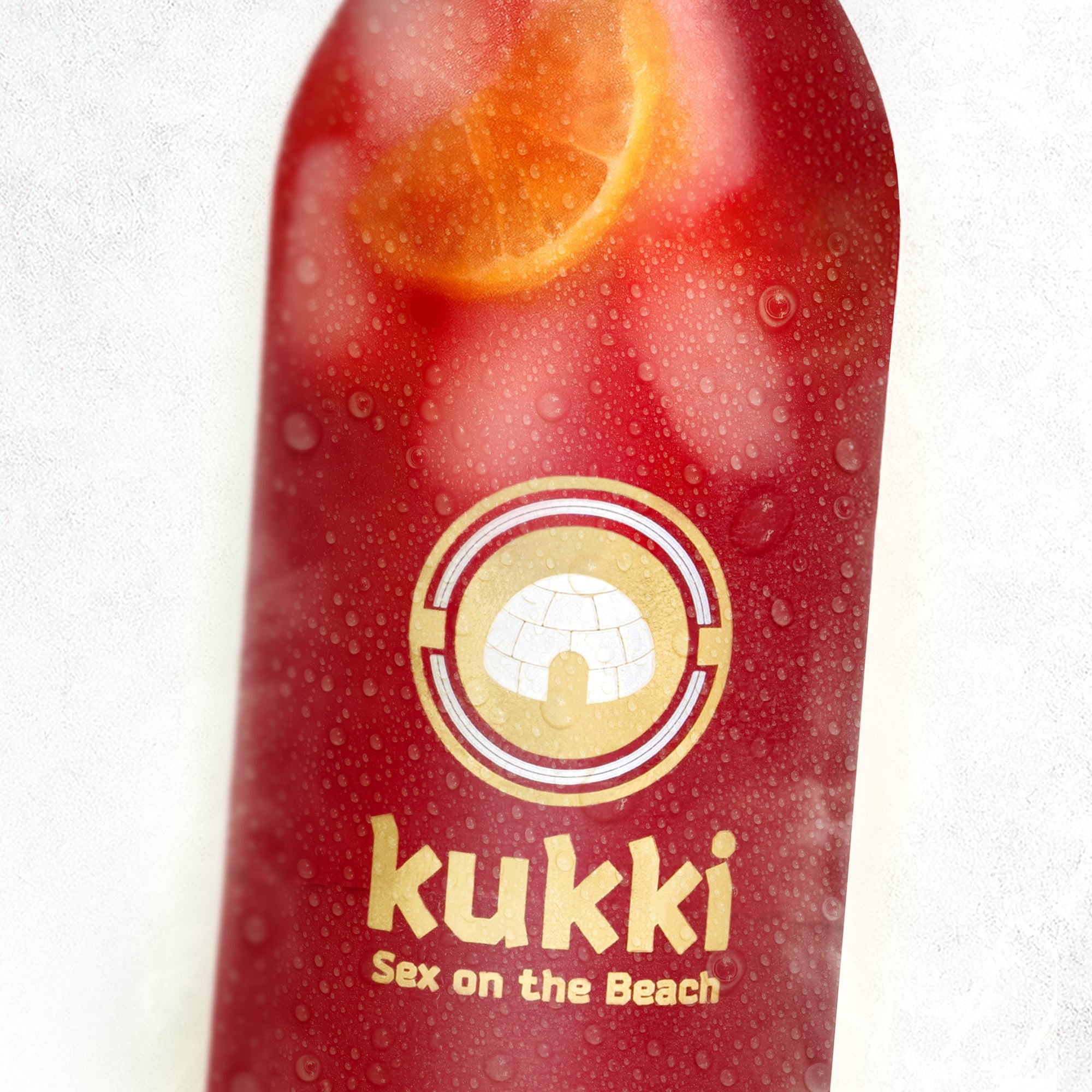 kukki Cocktail Sex on the Beach in roter Flasche mit Zitronenscheibe und Kondenswassertropfen