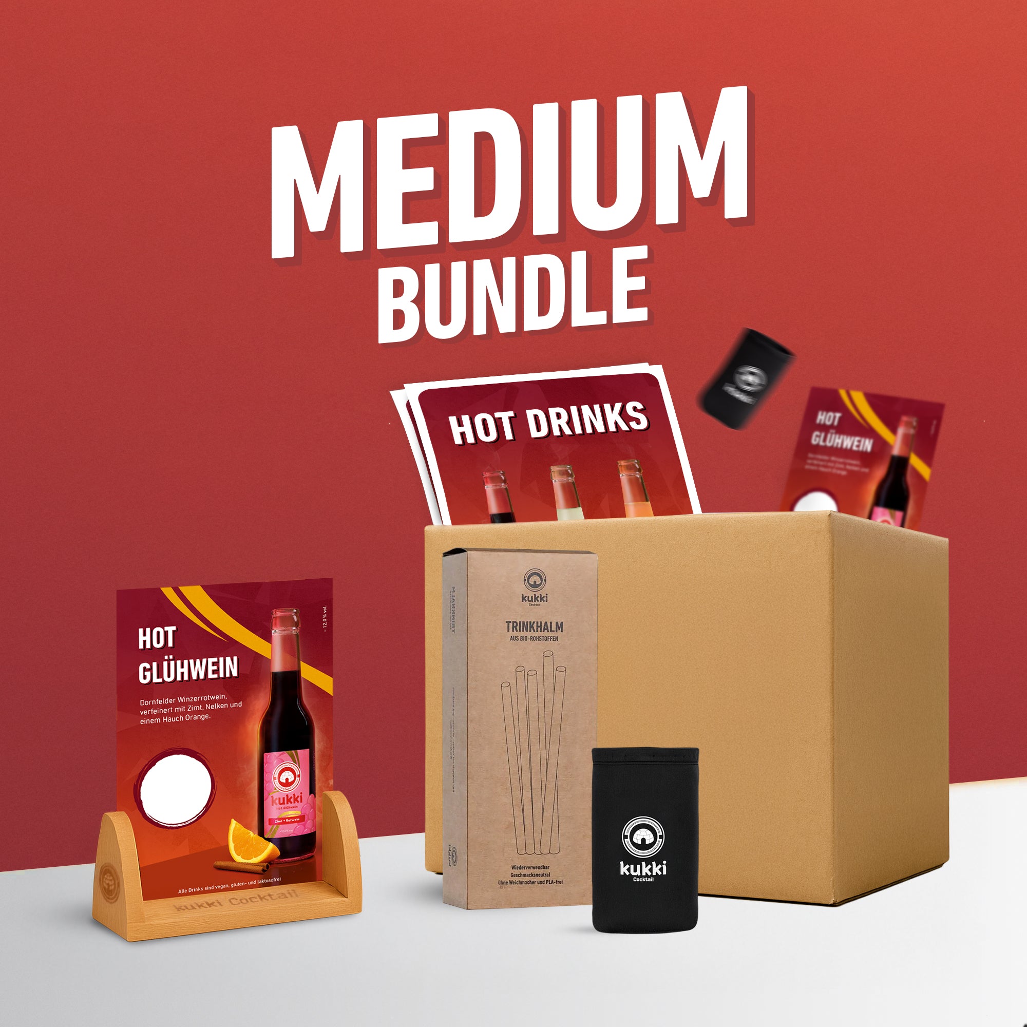 medium bundle von kukki mit hot glühwein, bio-trinkhalmen und cocktail sleeve vor rotem hintergrund