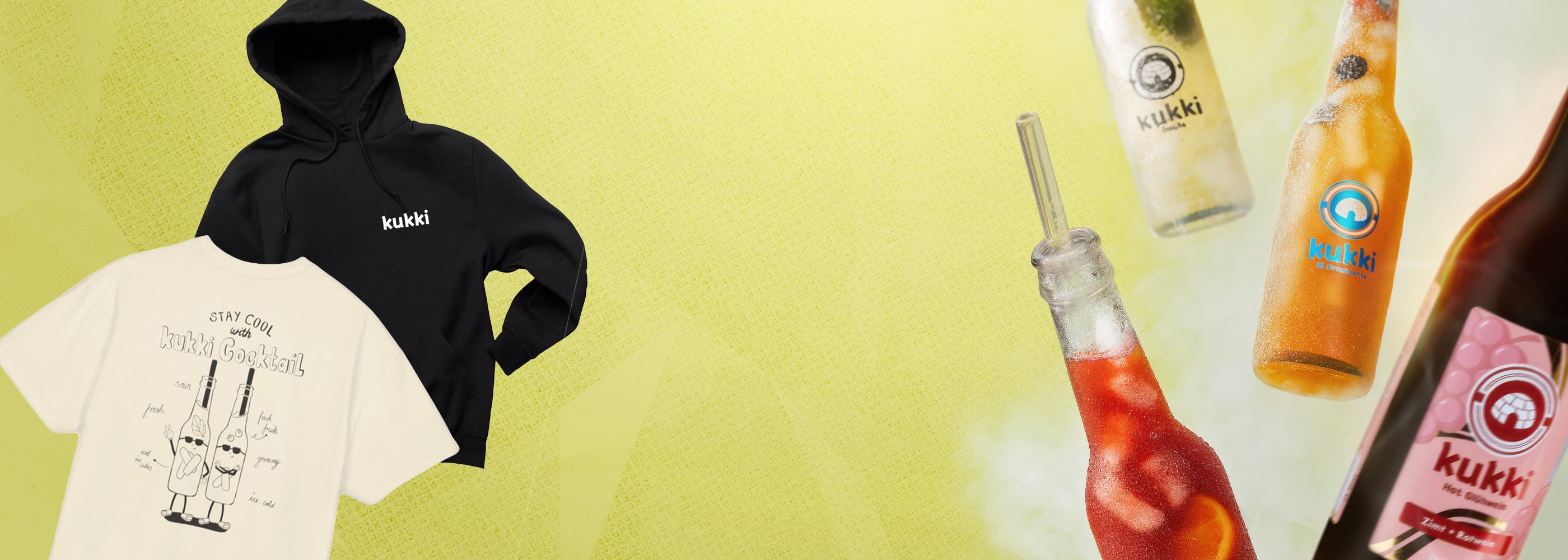 Zwei Bekleidungsstücke mit kukki Cocktail Branding neben vier gefrorenen Glasflaschen mit bunten kukki Etiketten auf hellgelbem Hintergrund.