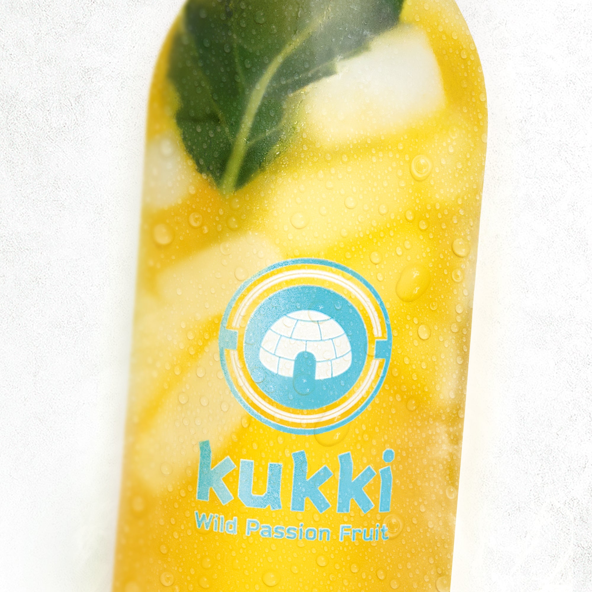 Gelber tiefgekühlter kukki Cocktail Wild Passion Fruit mit grünem Blatt im Inneren vor hellem Hintergrund.