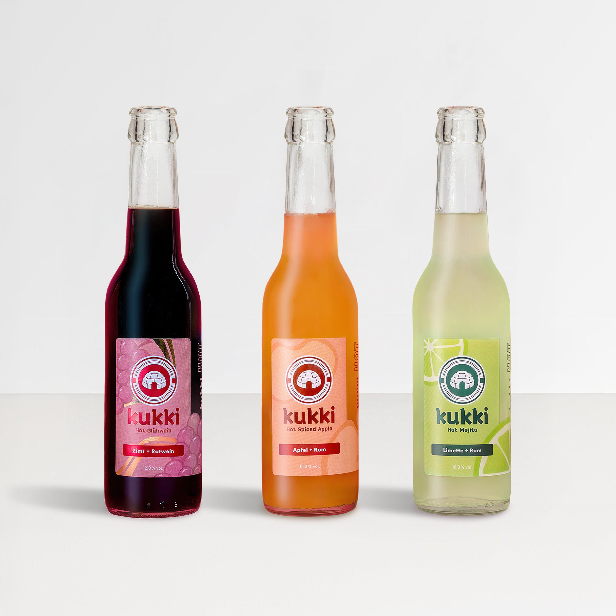Drei Glasflaschen kukki Cocktail mit den Sorten Glühwein, Spiced Apple und Mojito