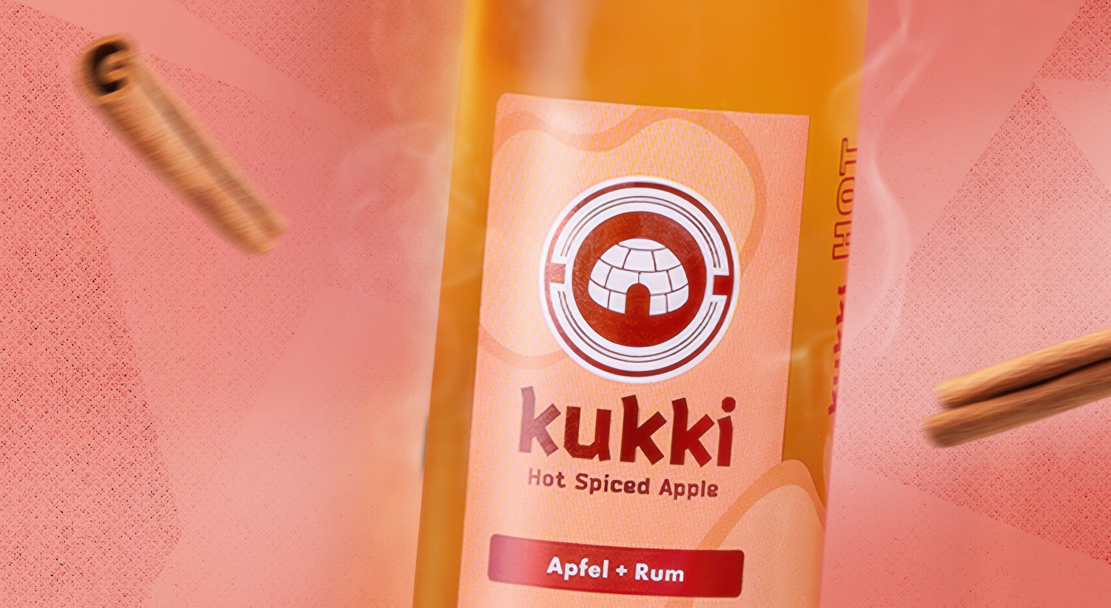 kukki Cocktail Hot Spiced Apple in Glasflasche mit Apfel und Rum, umgeben von Zimtstangen