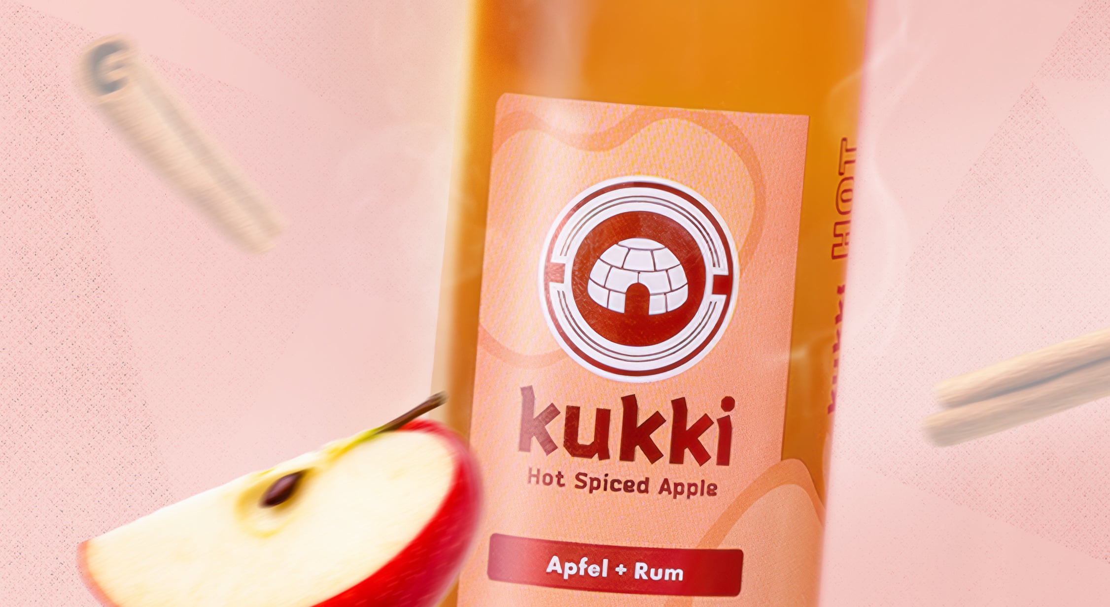 kukki Cocktail Hot Spiced Apple Apfel Rum in Glasflasche mit Dampf und Apfelscheibe vor Zimtstangen