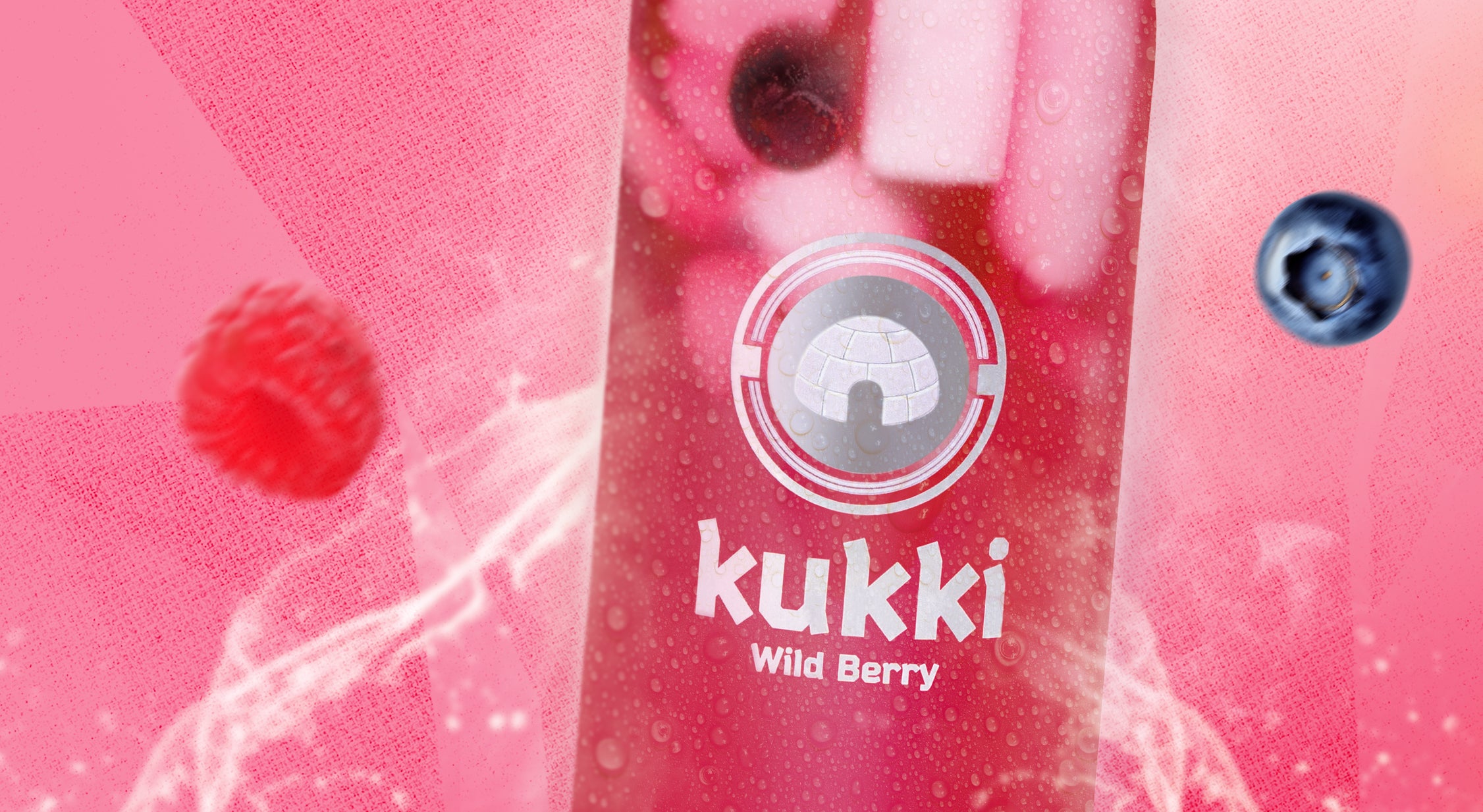 kukki Cocktail Wild Berry in einer Glasflasche mit Eiswürfeln, umgeben von Himbeeren und Blaubeeren vor pinkem Hintergrund