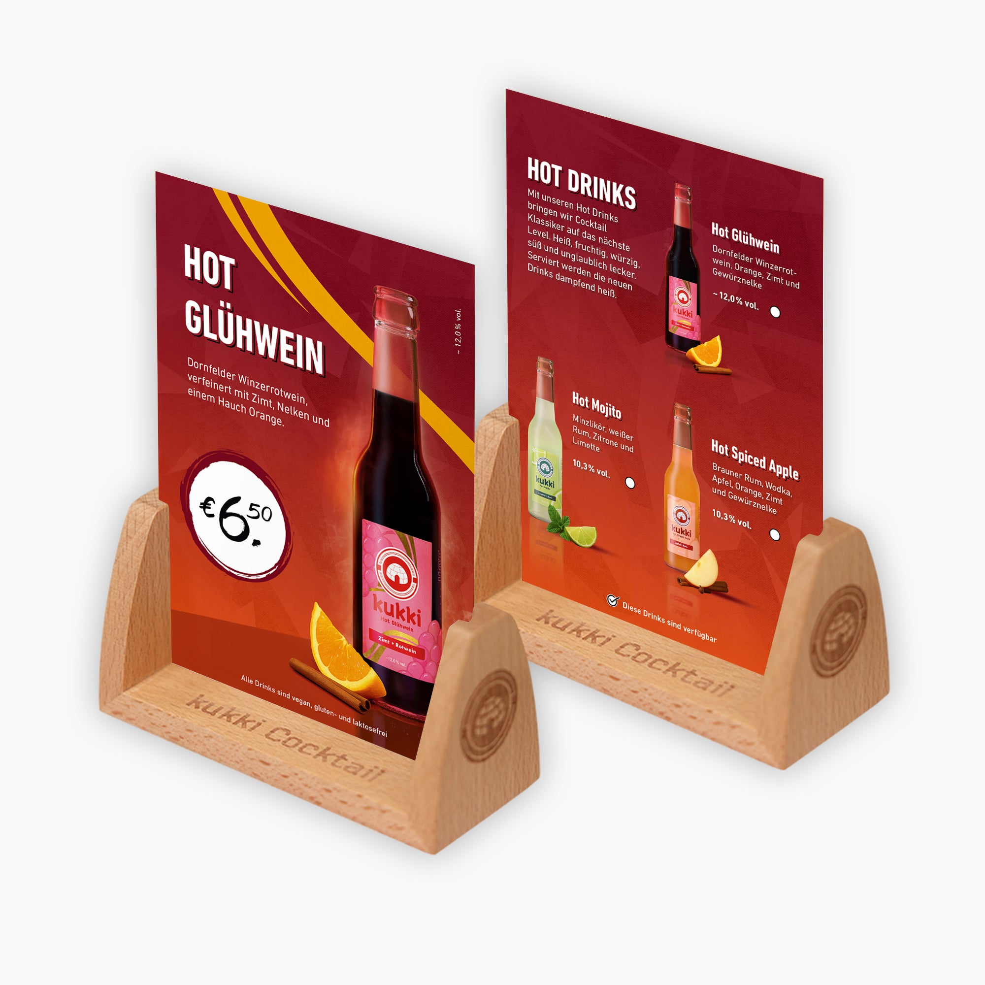 Zwei hölzerne Tischaufsteller mit roten Werbekarten für küchenfertige kukki Hot Cocktail Getränke in Glasflaschen mit Zimtstange und Orangenscheibe